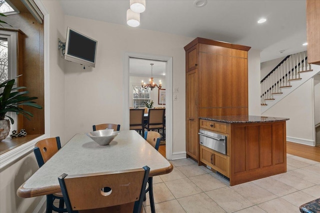 kitchen featuring dark stone counters, light tile patterned flooring, hanging light fixtures, and a notable chandelier