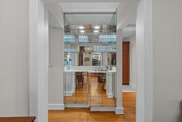 bar with sink and light hardwood / wood-style flooring