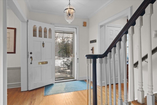 entrance foyer with an inviting chandelier, ornamental molding, and light hardwood / wood-style flooring