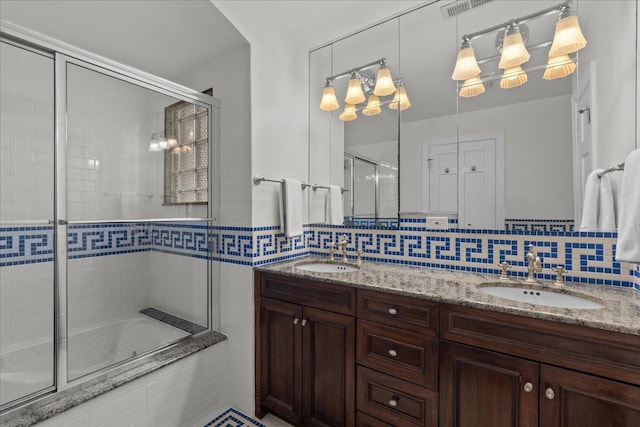 bathroom featuring combined bath / shower with glass door, vanity, and backsplash