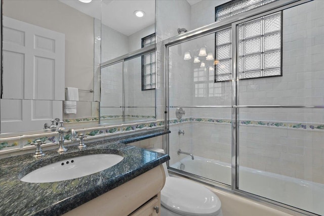 full bathroom featuring vanity, toilet, and bath / shower combo with glass door