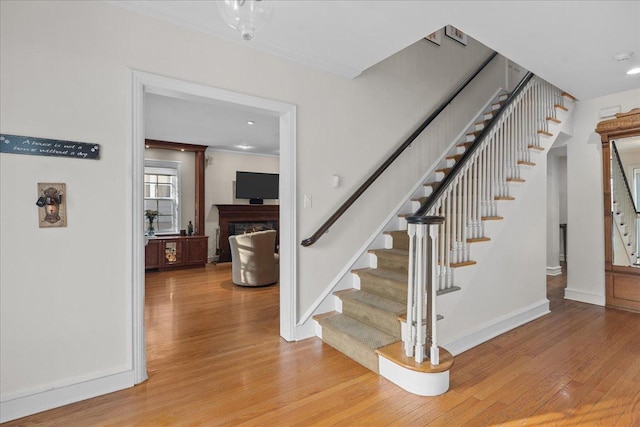 stairs with crown molding and wood-type flooring