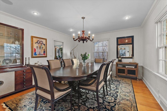 dining room featuring ornamental molding, light wood-type flooring, and a notable chandelier