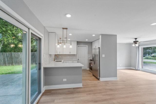 kitchen with kitchen peninsula, stainless steel refrigerator with ice dispenser, light hardwood / wood-style floors, white cabinetry, and hanging light fixtures