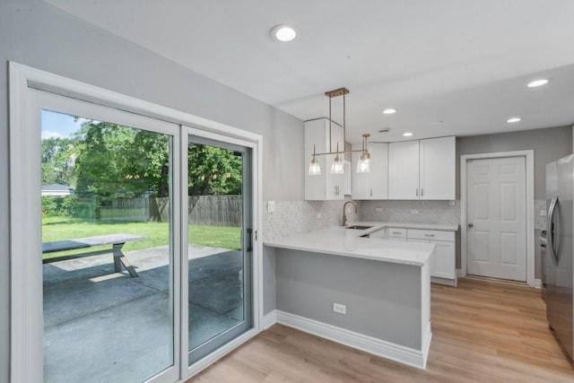 kitchen with white cabinets, plenty of natural light, kitchen peninsula, and hanging light fixtures