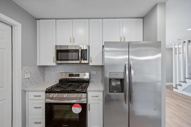 kitchen with light stone countertops, appliances with stainless steel finishes, backsplash, light hardwood / wood-style floors, and white cabinetry