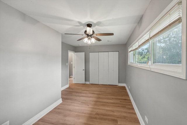 unfurnished bedroom with a closet, light hardwood / wood-style flooring, and ceiling fan