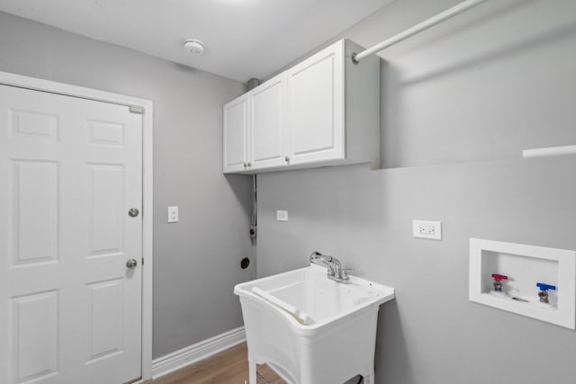 washroom featuring sink, hookup for a washing machine, cabinets, and wood-type flooring