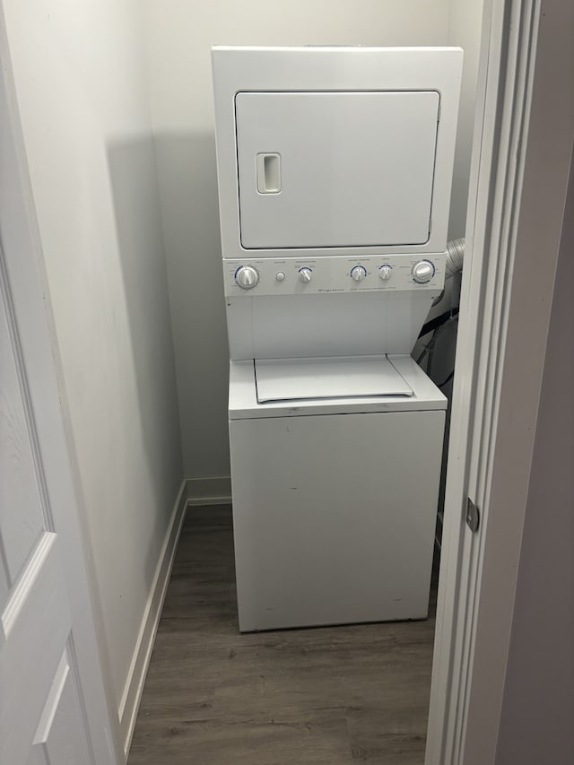 laundry area featuring stacked washer and dryer and dark wood-type flooring