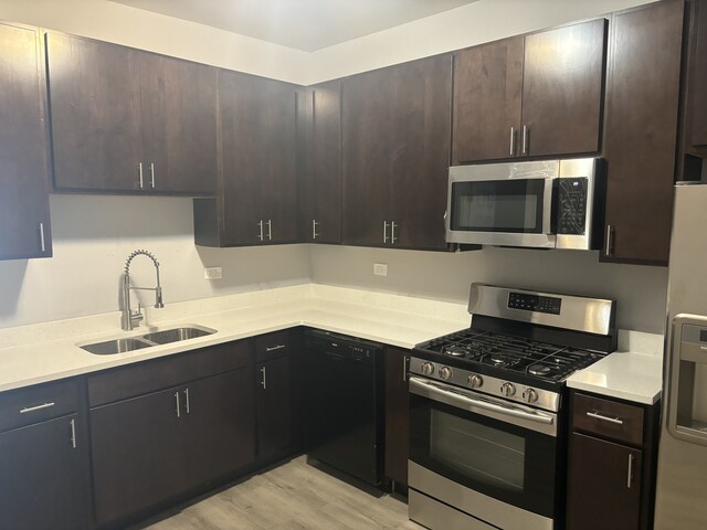 kitchen with sink, light wood-type flooring, stainless steel appliances, and dark brown cabinetry