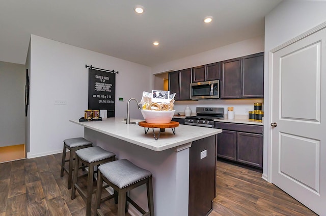 kitchen featuring kitchen peninsula, a kitchen breakfast bar, dark brown cabinetry, stainless steel appliances, and dark hardwood / wood-style floors