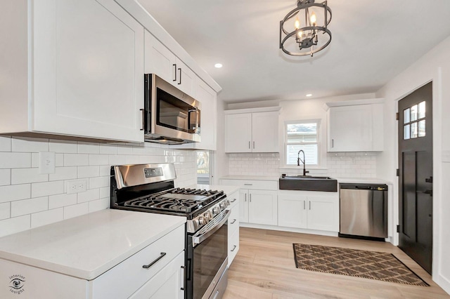 kitchen featuring sink, white cabinetry, tasteful backsplash, appliances with stainless steel finishes, and light hardwood / wood-style floors