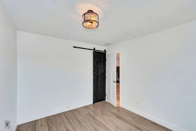 unfurnished room featuring light hardwood / wood-style floors and a barn door