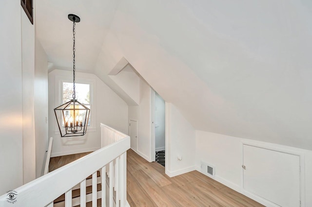 bonus room with lofted ceiling, a notable chandelier, and light wood-type flooring