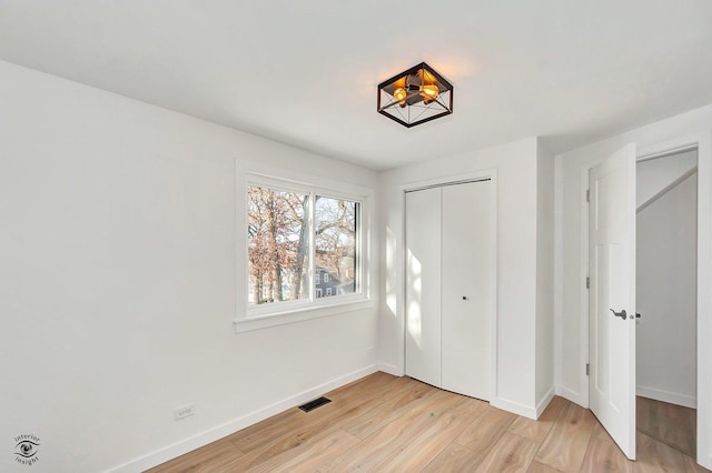 unfurnished bedroom with light wood-type flooring and a closet