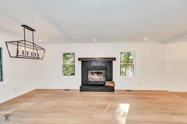 unfurnished living room featuring a brick fireplace and light wood-type flooring