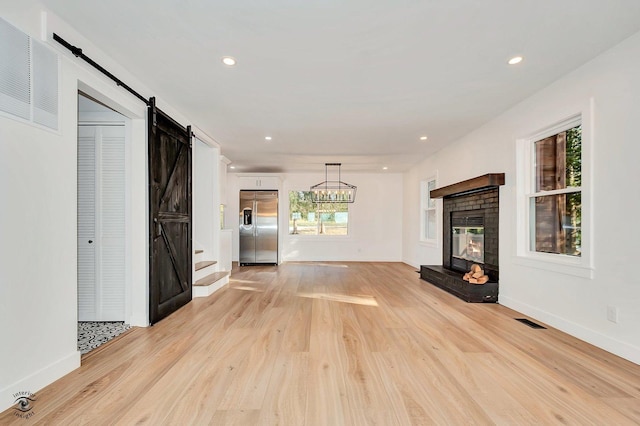 unfurnished living room with a barn door and light wood-type flooring