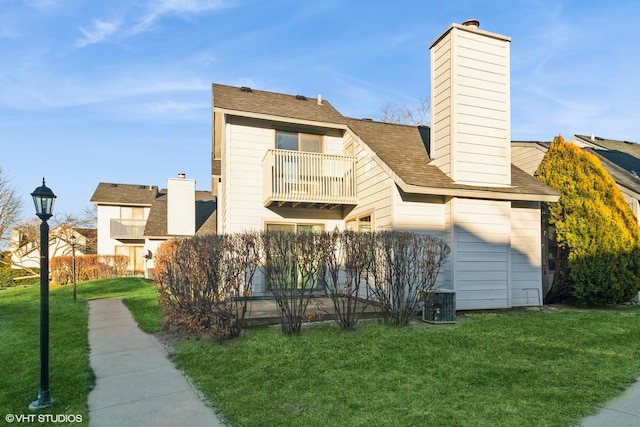 rear view of house with a yard and a balcony