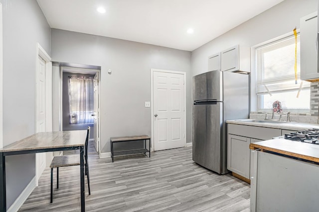 kitchen with decorative backsplash, stainless steel fridge, light hardwood / wood-style floors, and gray cabinets