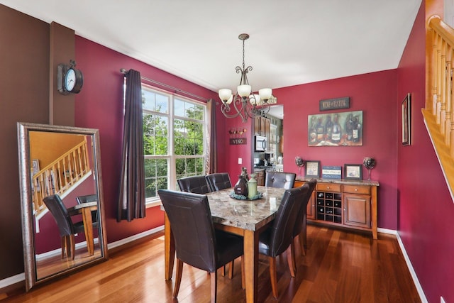 dining space with hardwood / wood-style floors and an inviting chandelier