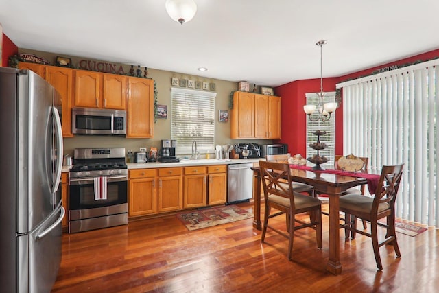 kitchen with pendant lighting, sink, dark hardwood / wood-style floors, appliances with stainless steel finishes, and a chandelier