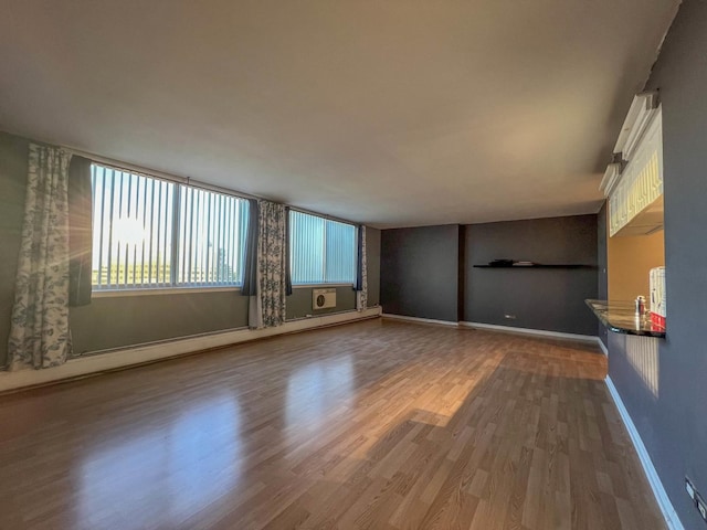 empty room with hardwood / wood-style floors and a baseboard heating unit