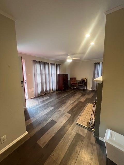 interior space with crown molding, ceiling fan, and dark wood-type flooring