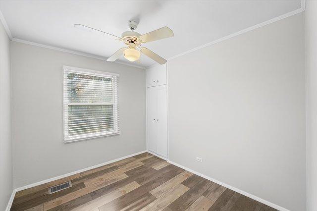 empty room featuring ceiling fan, dark hardwood / wood-style floors, and ornamental molding