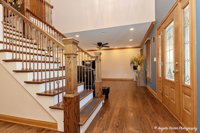 entryway featuring ceiling fan with notable chandelier, ornamental molding, and dark wood-type flooring