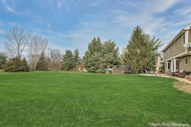 view of yard featuring a playground, a trampoline, and a patio