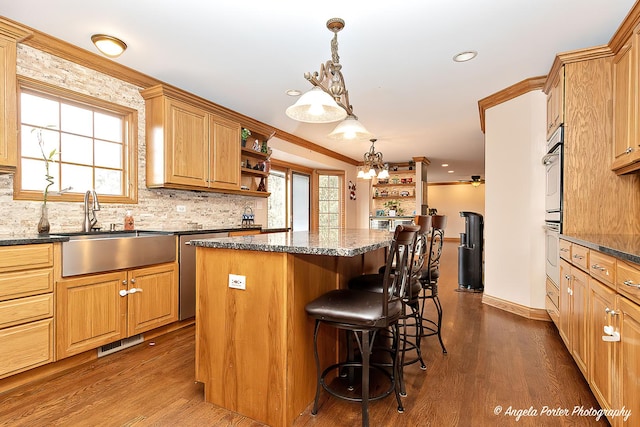 kitchen with tasteful backsplash, dark stone counters, sink, dark hardwood / wood-style floors, and stainless steel gas stovetop