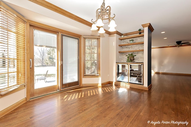 doorway to outside with crown molding, ceiling fan with notable chandelier, and hardwood / wood-style flooring