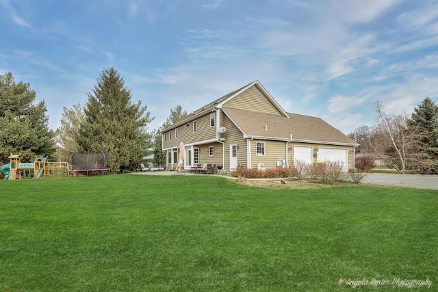 view of front of home with a front yard, a trampoline, a playground, and a garage