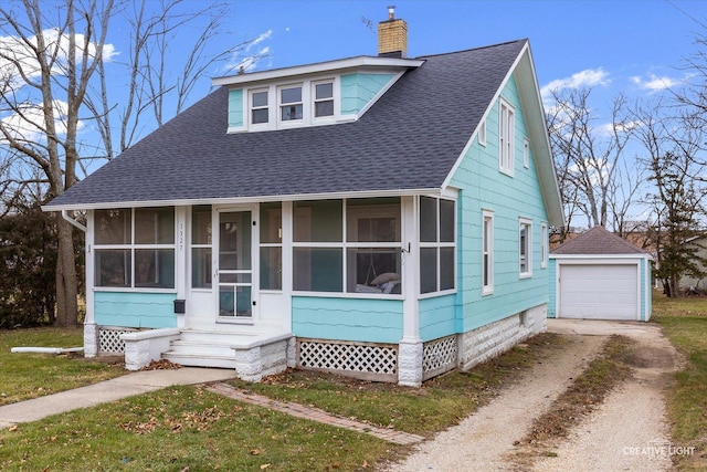 bungalow with a sunroom, a garage, and an outbuilding