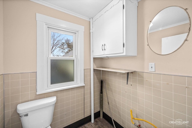 bathroom with crown molding, toilet, and tile walls