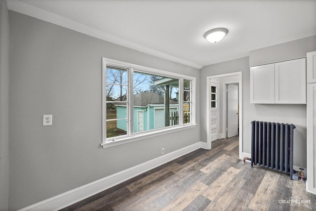 empty room featuring dark hardwood / wood-style flooring and radiator heating unit