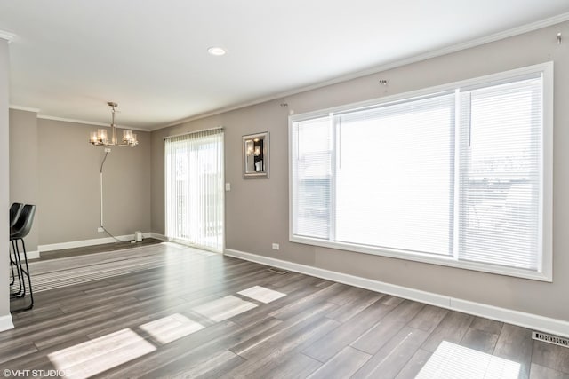 unfurnished dining area featuring baseboards, wood finished floors, and crown molding