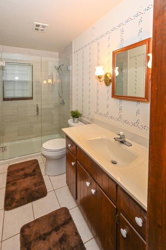 bathroom featuring tile patterned flooring, vanity, toilet, and a shower with shower door