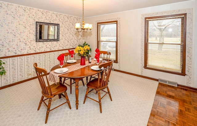 dining space with parquet floors, an inviting chandelier, and plenty of natural light