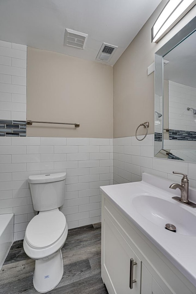 bathroom with vanity, wood-type flooring, tile walls, and toilet