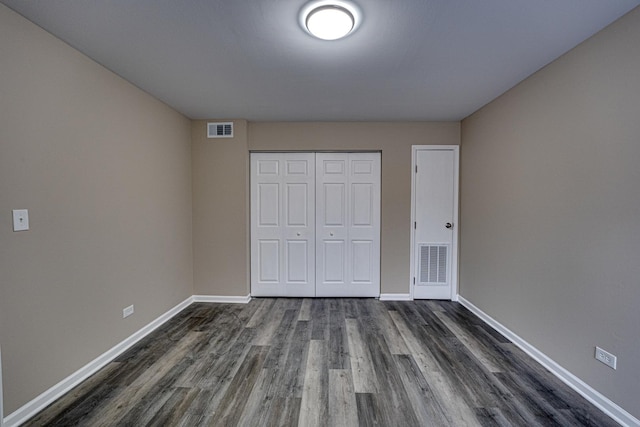 unfurnished bedroom with a closet and dark wood-type flooring