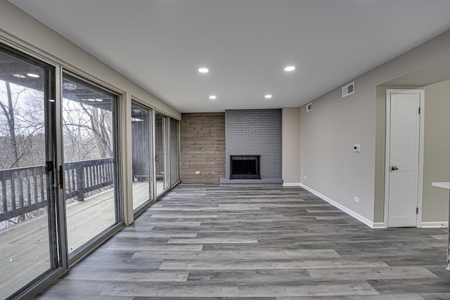 unfurnished living room with hardwood / wood-style flooring and a brick fireplace