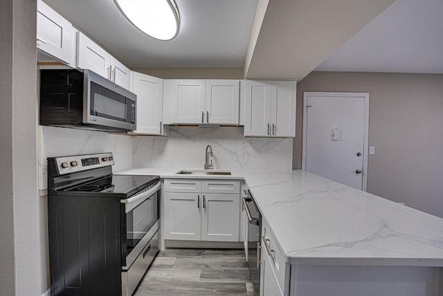 kitchen with white cabinets, sink, stainless steel appliances, and light hardwood / wood-style flooring