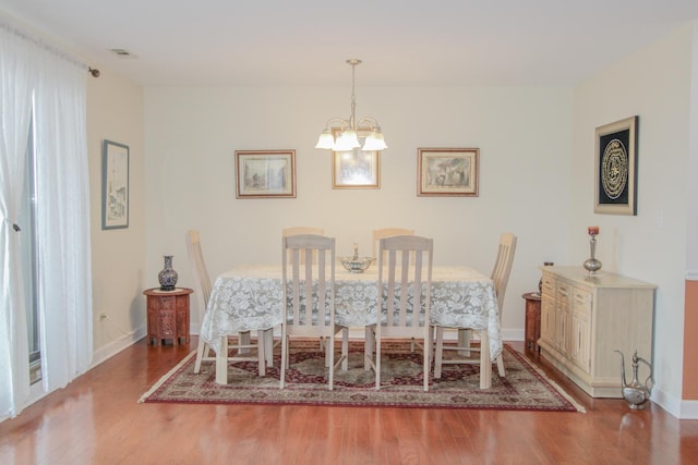 dining room with hardwood / wood-style flooring and an inviting chandelier