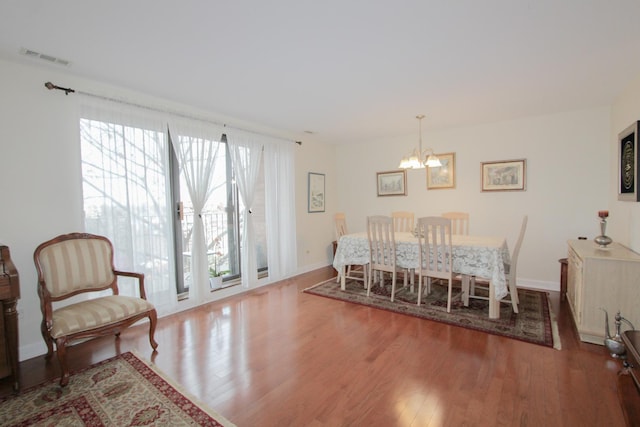 dining space featuring hardwood / wood-style flooring and an inviting chandelier