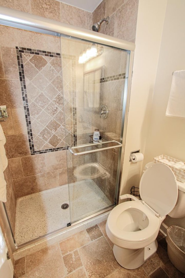 bathroom featuring toilet and a shower with door