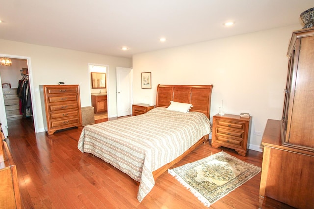 bedroom featuring connected bathroom, a spacious closet, a closet, and dark hardwood / wood-style floors