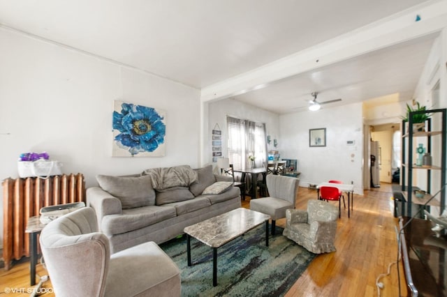 living room featuring beamed ceiling, ceiling fan, wood-type flooring, and radiator heating unit