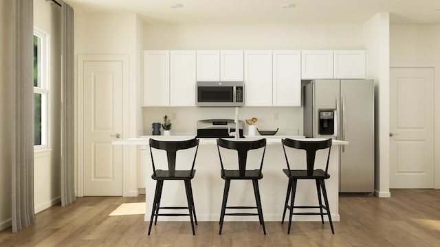 kitchen featuring light hardwood / wood-style flooring, white cabinets, a center island with sink, and appliances with stainless steel finishes