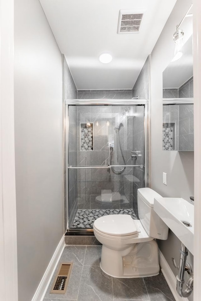 bathroom featuring tile patterned floors, a shower with door, and toilet